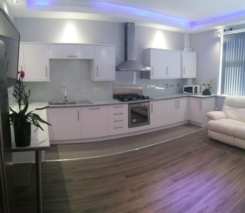 Modern open-plan kitchen with sleek white cabin...