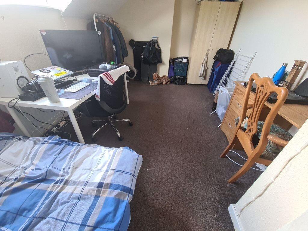 A cozy bedroom with a bed, desk, and personal i...