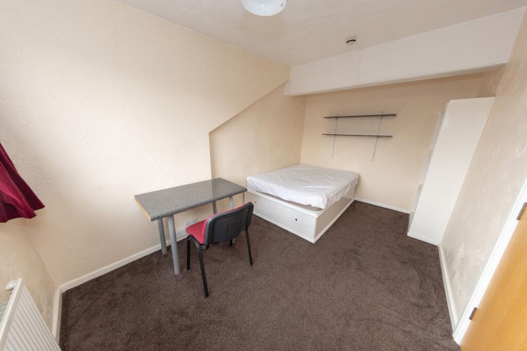 A modest-sized room featuring a single bed with...