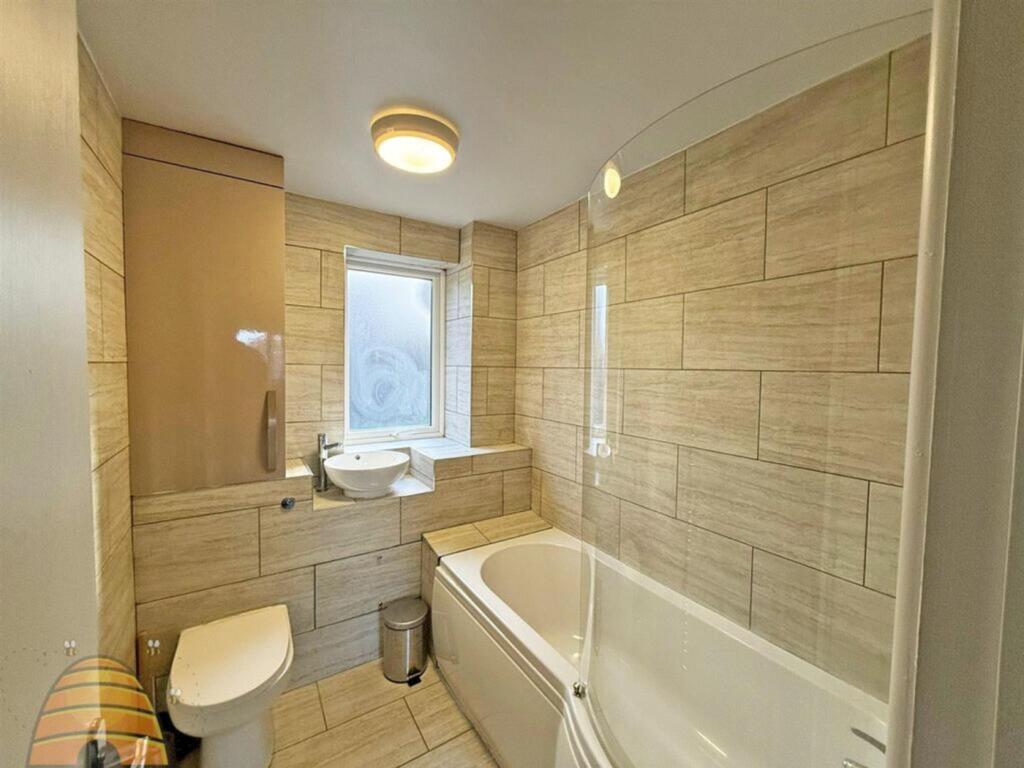 A spacious and modern bathroom featuring a bath...