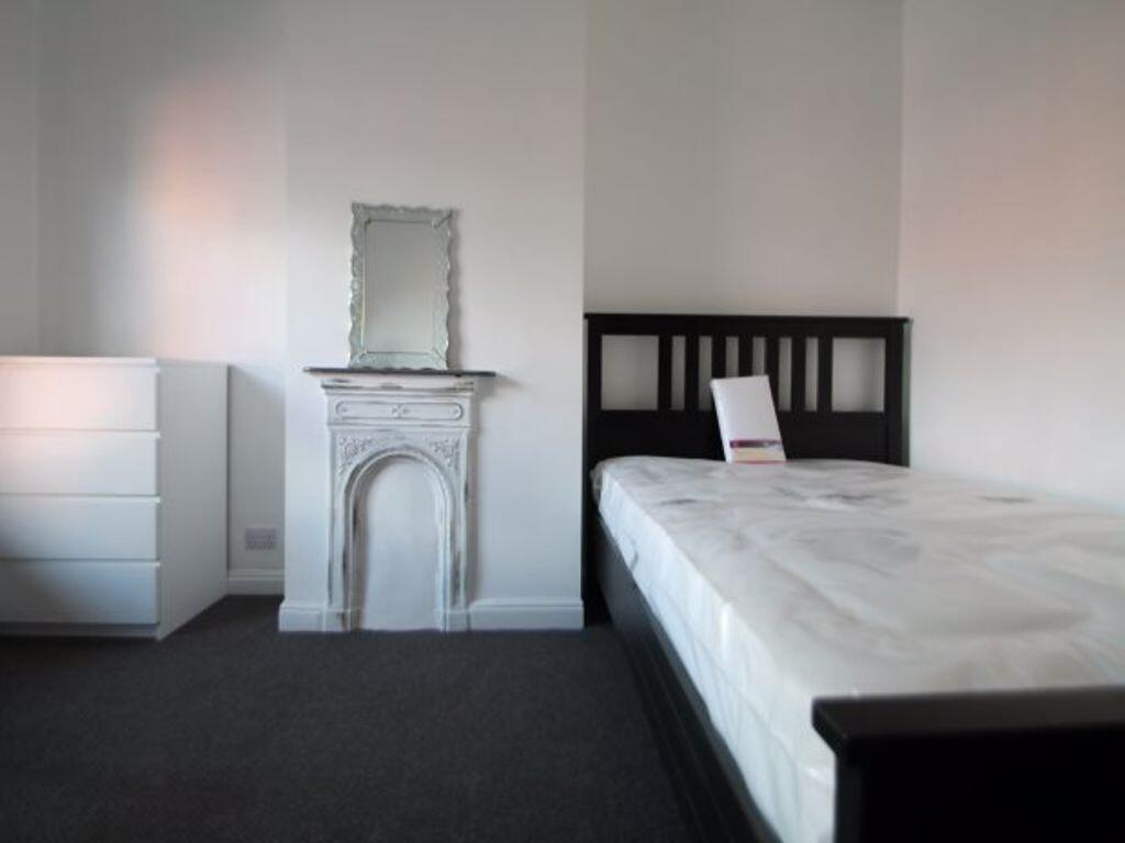 A tidy single bedroom featuring a dark wood bed...