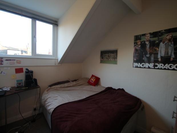 A cozy bedroom featuring a single bed with a be...