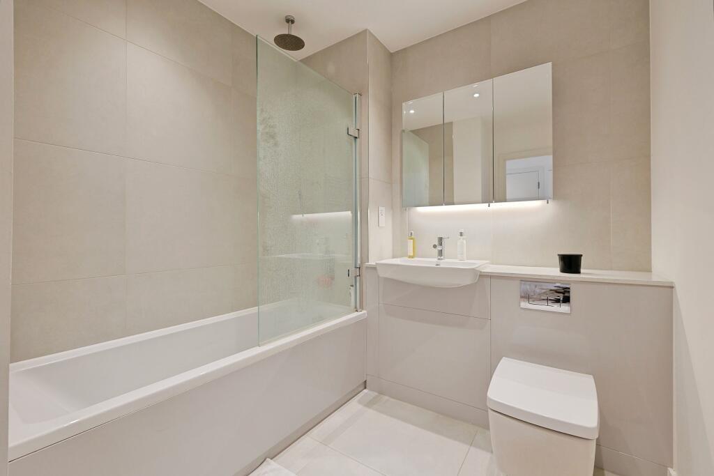 Modern bathroom with a sleek white bathtub, a s...