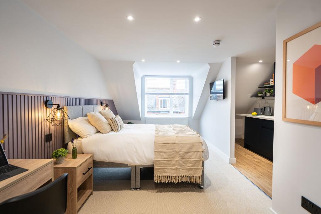 A modern, well-lit bedroom featuring a comforta...