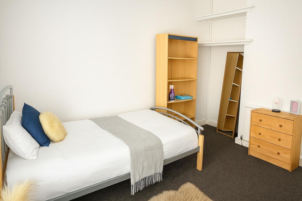 A neat and inviting single bedroom featuring a ...