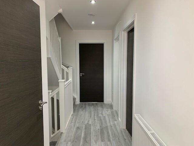 A clean, modern hallway with light grey wood fl...