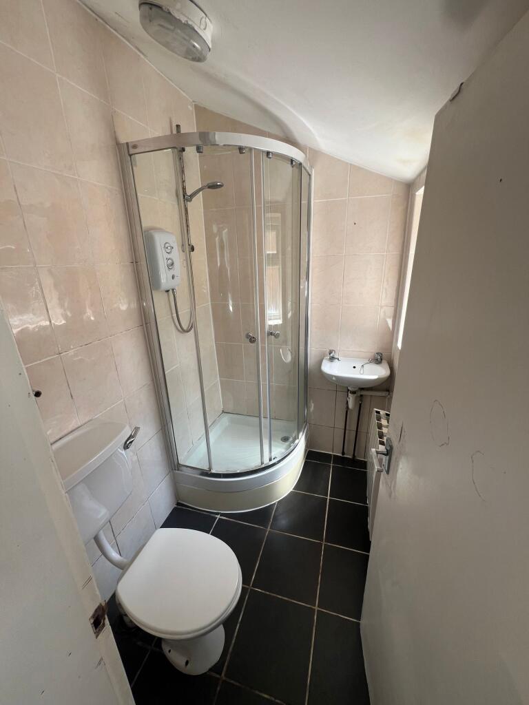 Compact bathroom featuring a modern curved glas...