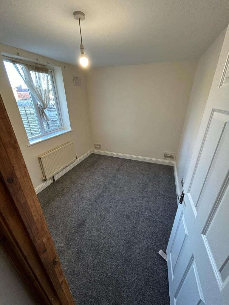 A tidy bedroom with a window allowing natural l...