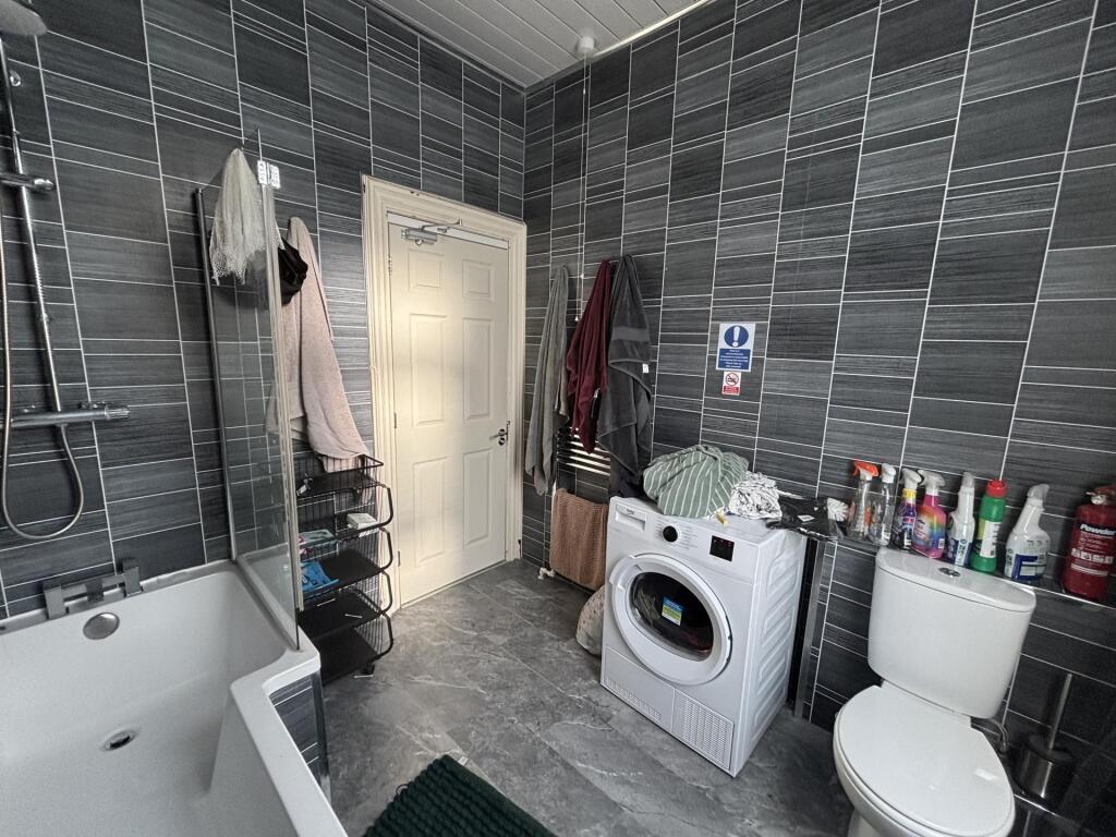 Modern tiled bathroom with a bathtub and wall-m...