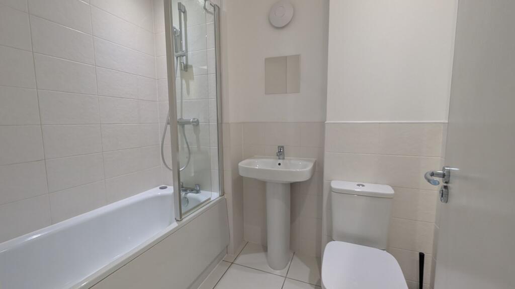 Bright, modern bathroom with a tiled shower-ove...