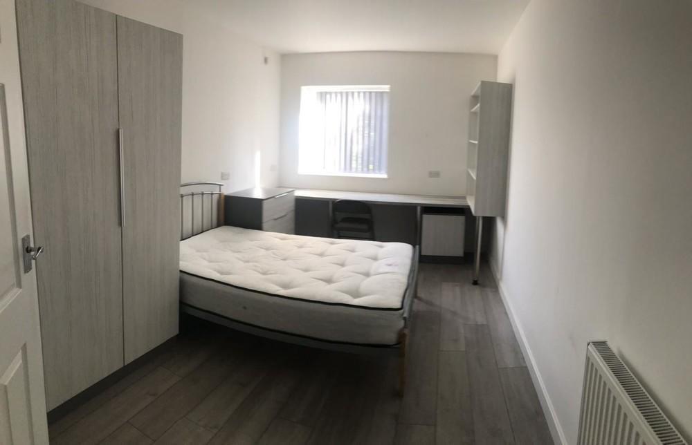 A tidy single bedroom featuring a bed, wardrobe...