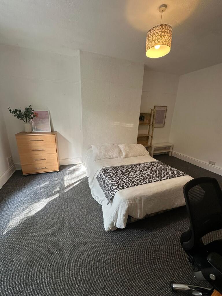 A well-lit, spacious master bedroom with a comf...