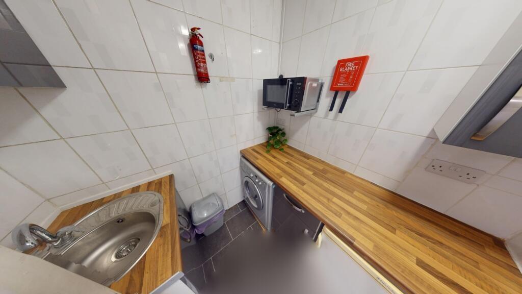 A compact, modern kitchen featuring wooden coun...