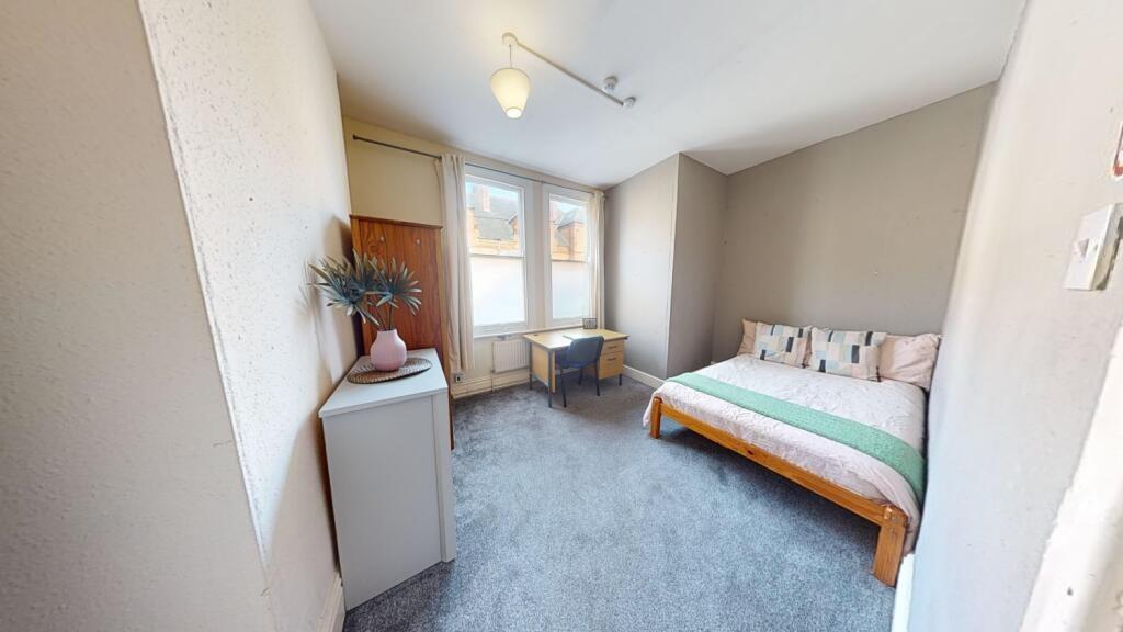 A bright and cozy single bedroom featuring a co...