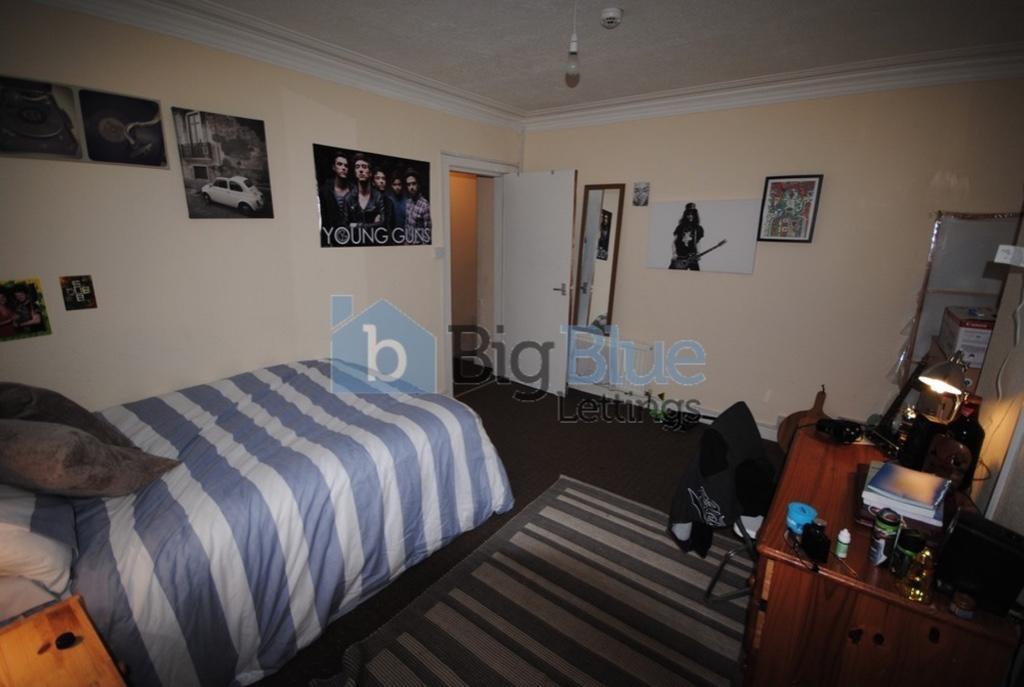 A cozy single bedroom with a striped bedspread,...