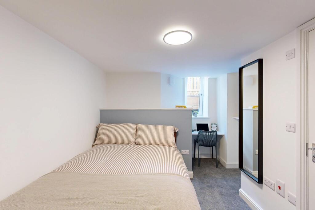 A bright and tidy bedroom featuring a comfortab...