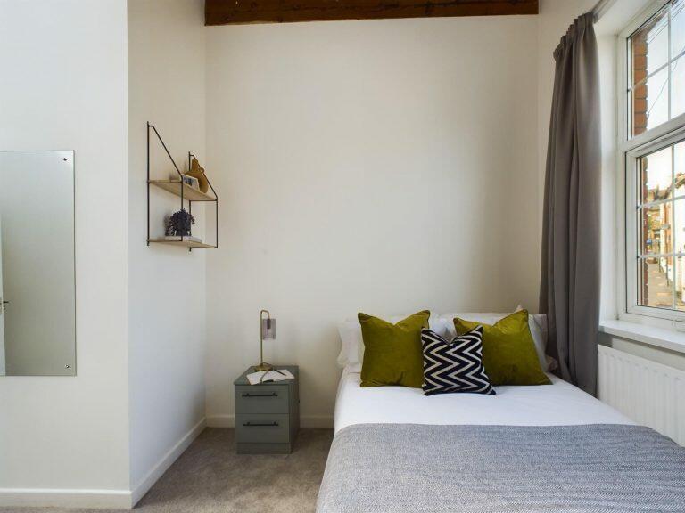 A cozy single bedroom featuring a neatly made b...