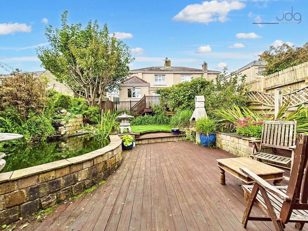 Spacious garden with a mixed of decking, artificial lawn and a pond