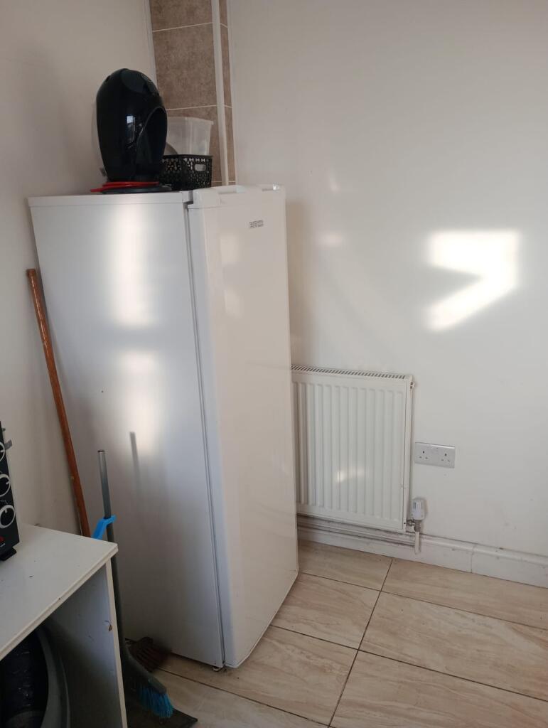 A simple kitchen area featuring a white fridge ...