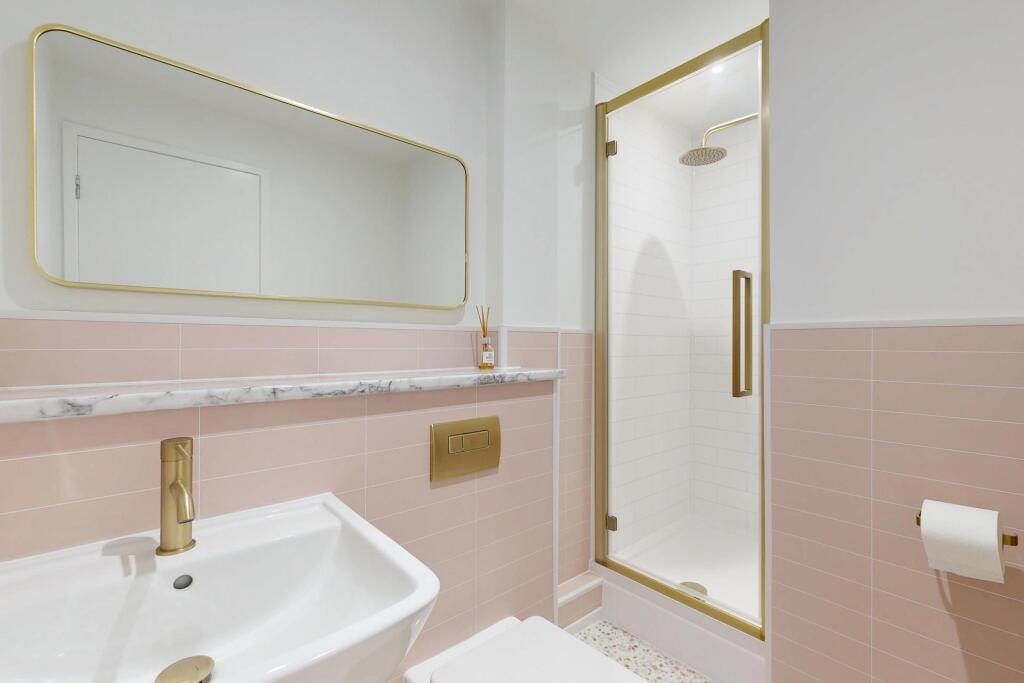 Bright, modern bathroom with pale pink subway t...