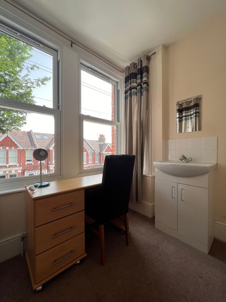 A neat and bright bedroom featuring a large win...