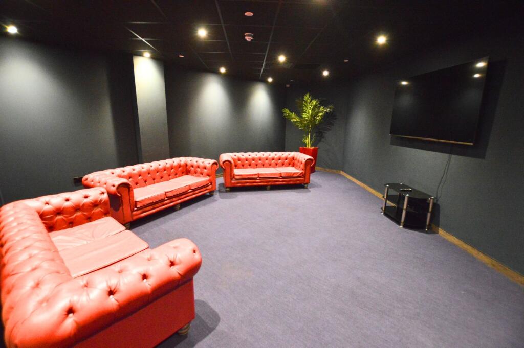 A stylish cinema room featuring three plush red...