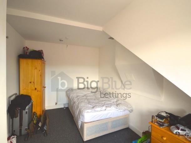 A cozy single bedroom with a neatly made bed po...