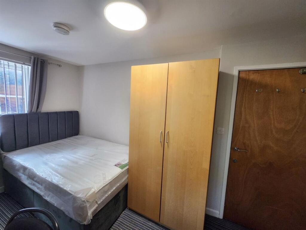 A tidy bedroom featuring a comfortable bed with...