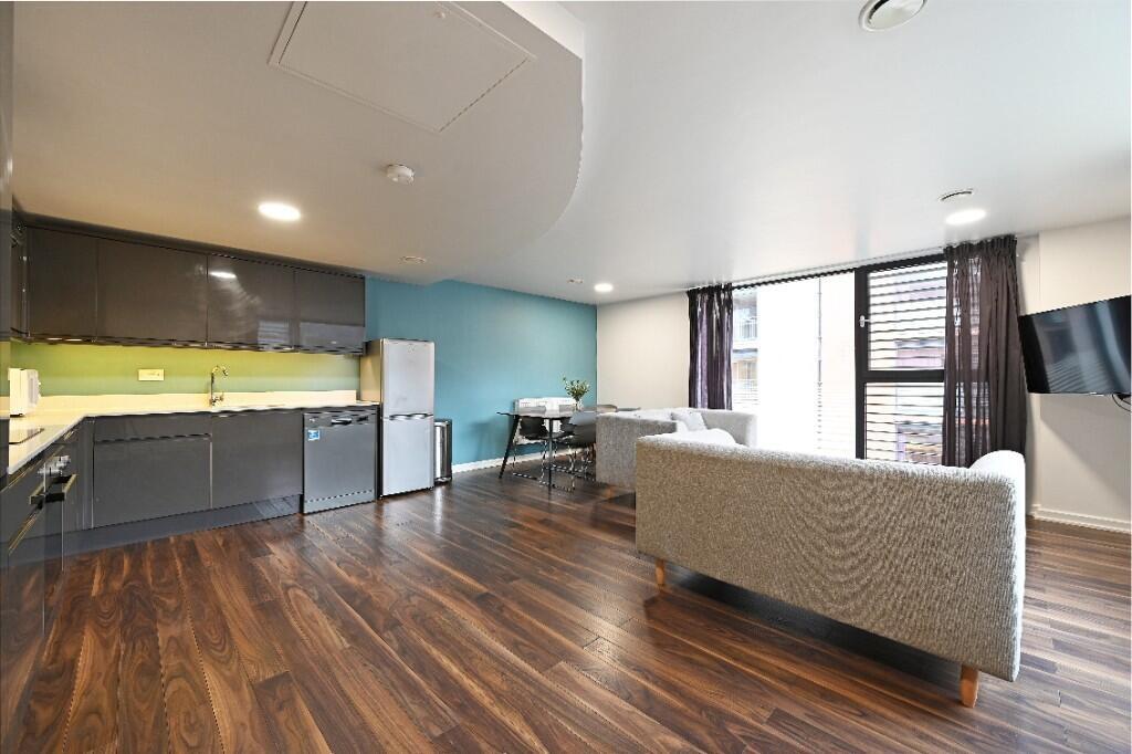 Modern living room with a sleek kitchen area, s...
