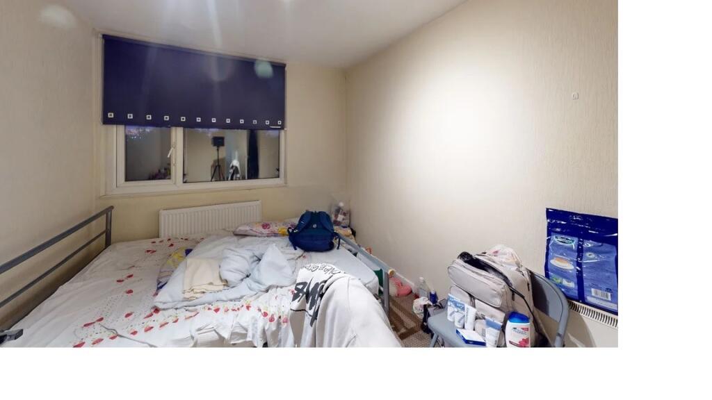 A modest single bedroom with a bed, a small des...