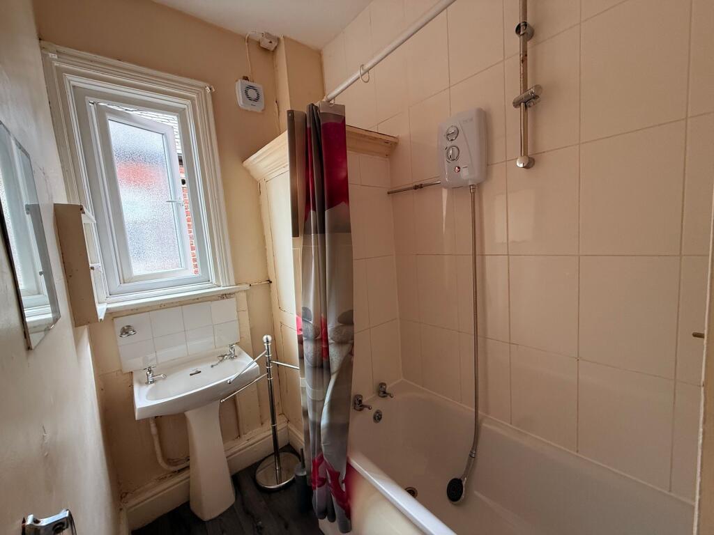 Bright bathroom with a tiled bath and shower, p...