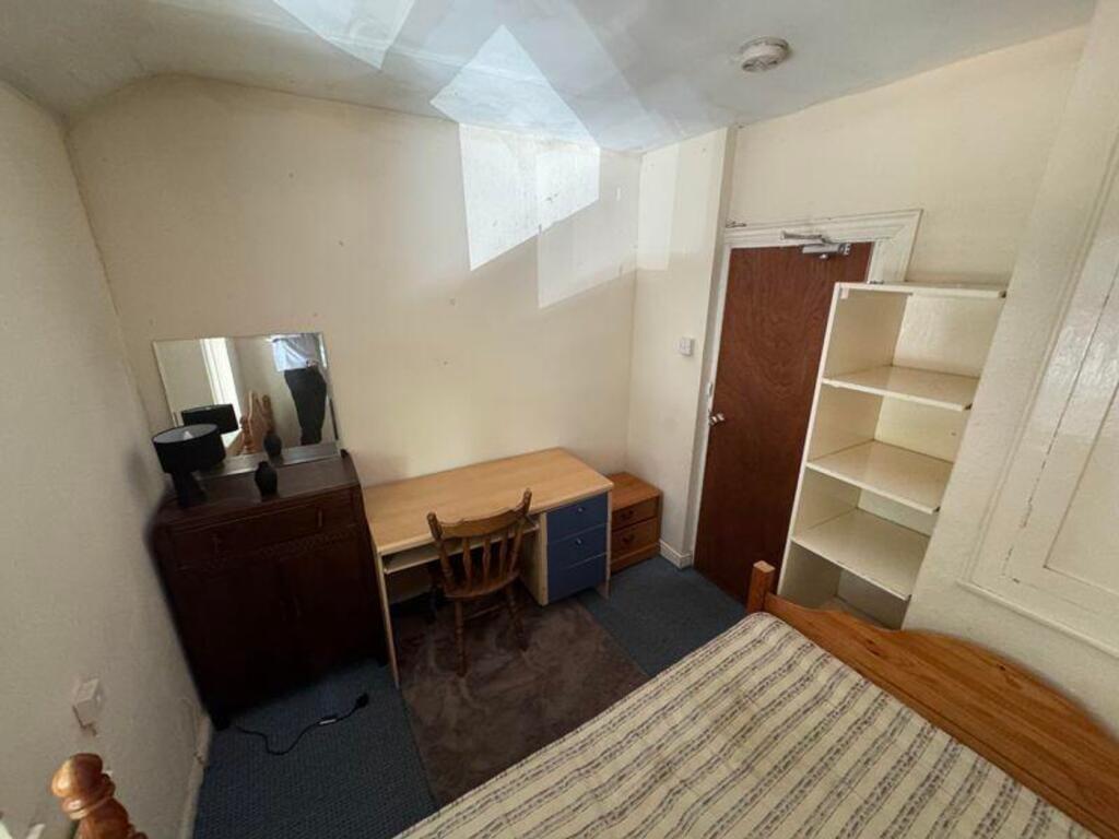 A cozy double bedroom with a desk and ample sto...