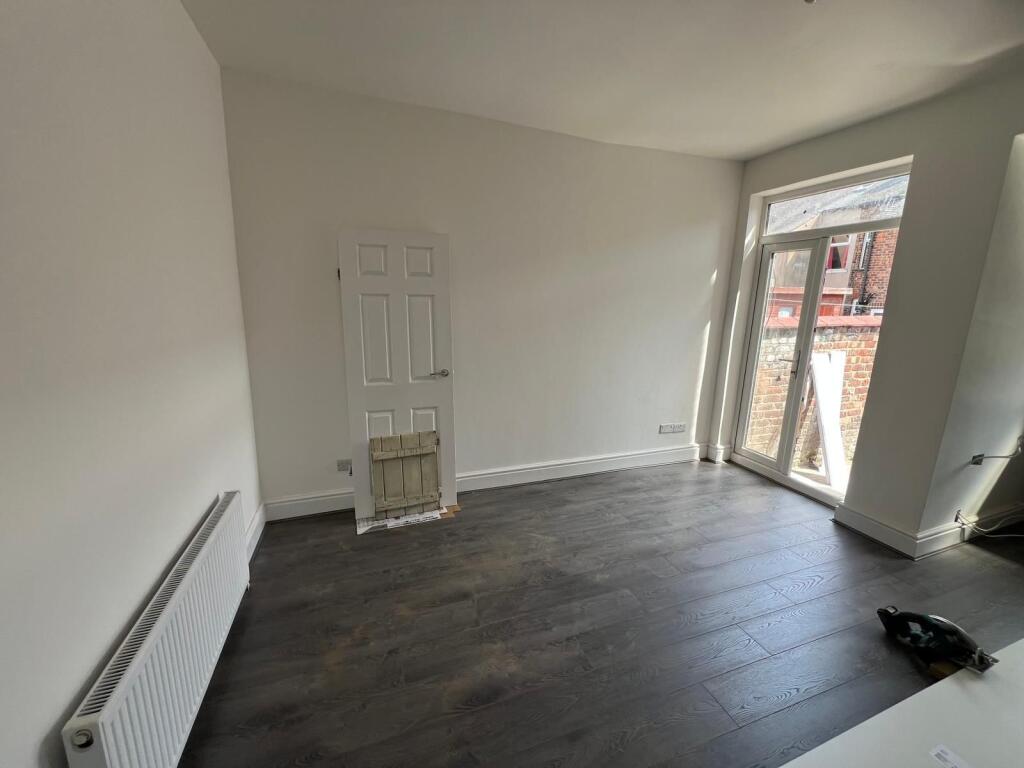 A bright double bedroom featuring dark wood flo...