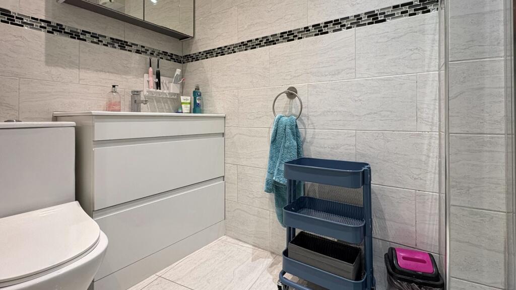 Modern tiled bathroom with a white vanity unit,...