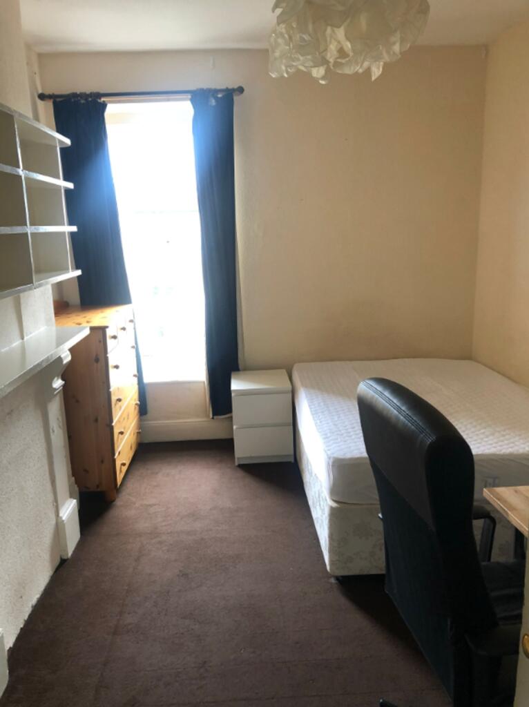 A tidy double bedroom with a single bed, desk, ...
