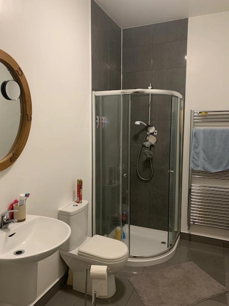 A modern bathroom featuring a curved glass show...