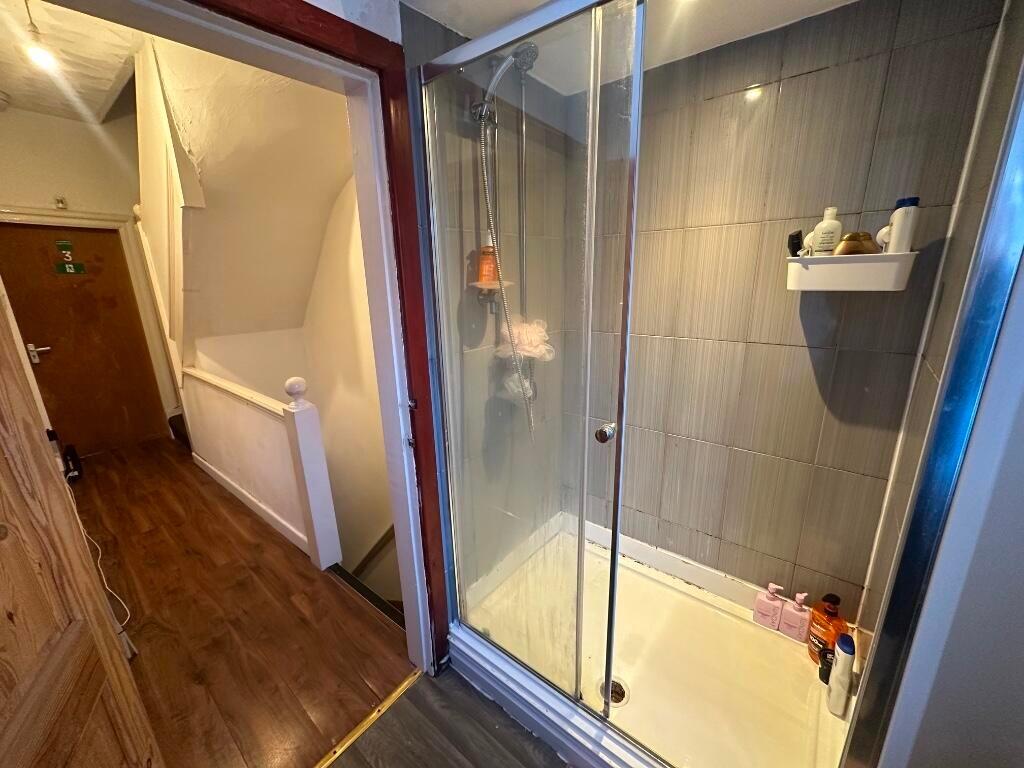 A compact bathroom featuring a glass-enclosed s...