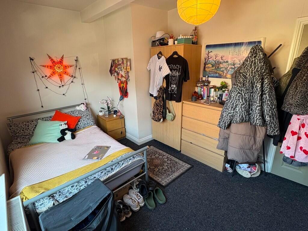 A cozy single bedroom with a neatly made bed, a...