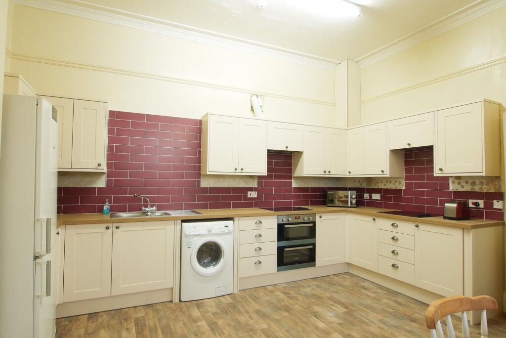 A spacious, clean kitchen with modern cream cab...