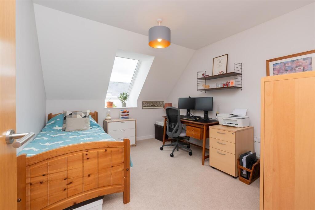 A bright and tidy single bedroom featuring a wo...