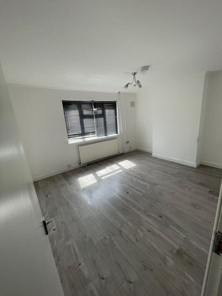 A bright, clean room with large window blinds a...
