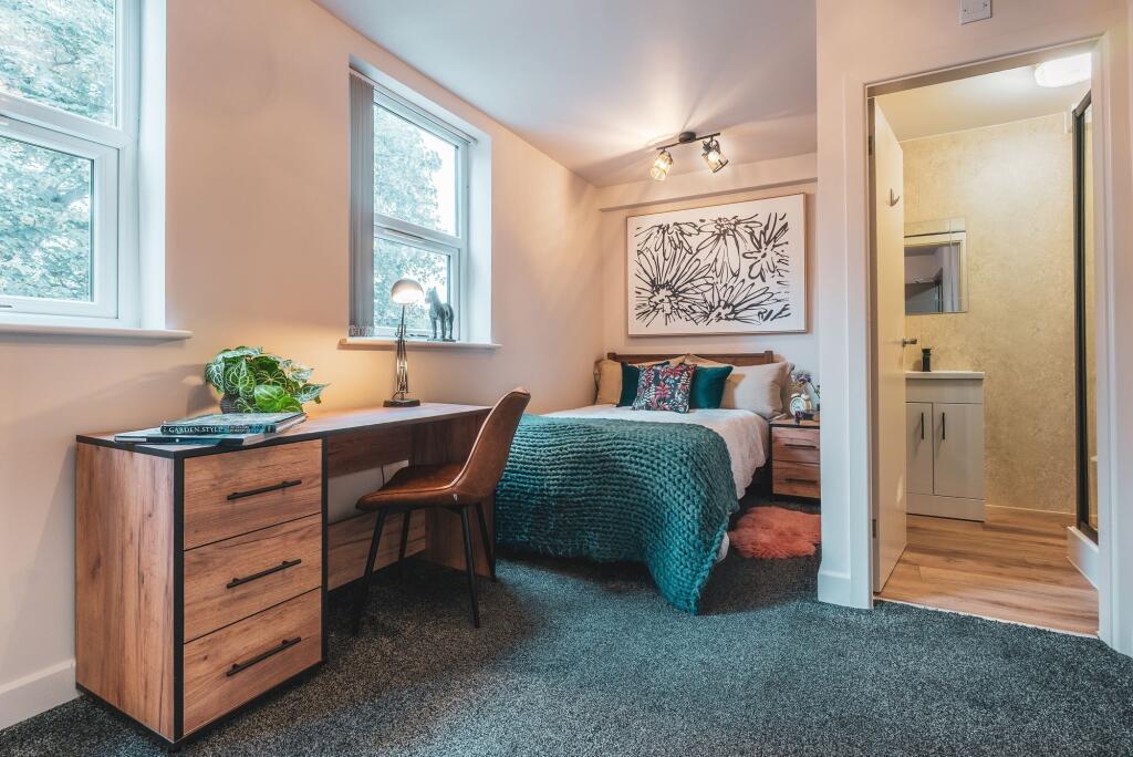A cozy and well-lit bedroom featuring a comfort...