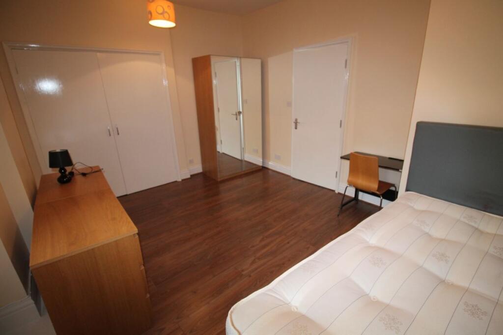 A neat and tidy bedroom featuring a wooden floo...