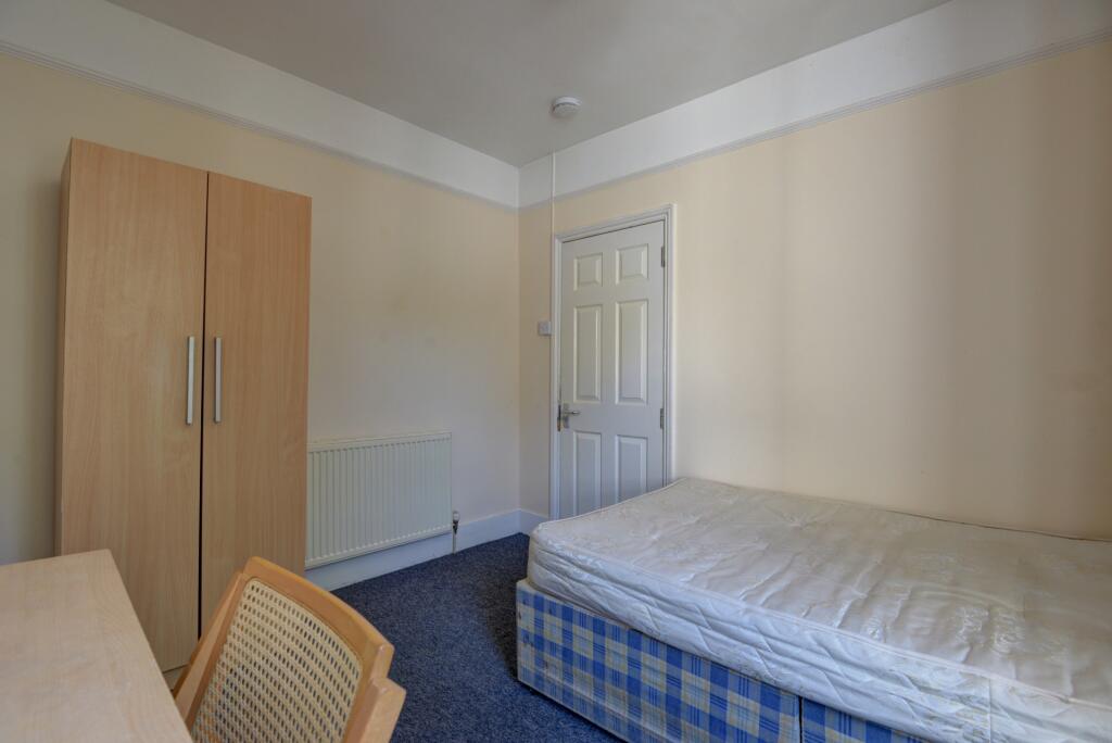 A simple and tidy single bedroom featuring a wo...