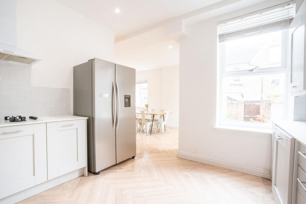 Bright and modern kitchen with white cabinetry,...