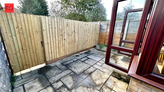 A private, paved garden area enclosed by a wood...