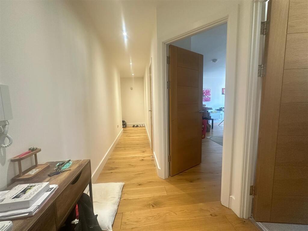 Bright and clean hallway with wooden flooring a...