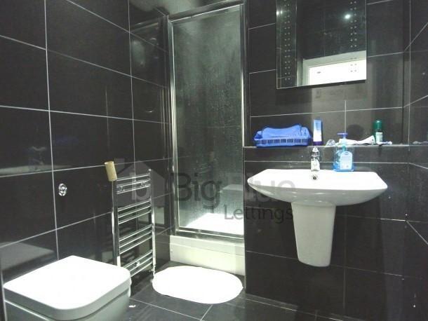 A modern bathroom featuring sleek black tiled w...