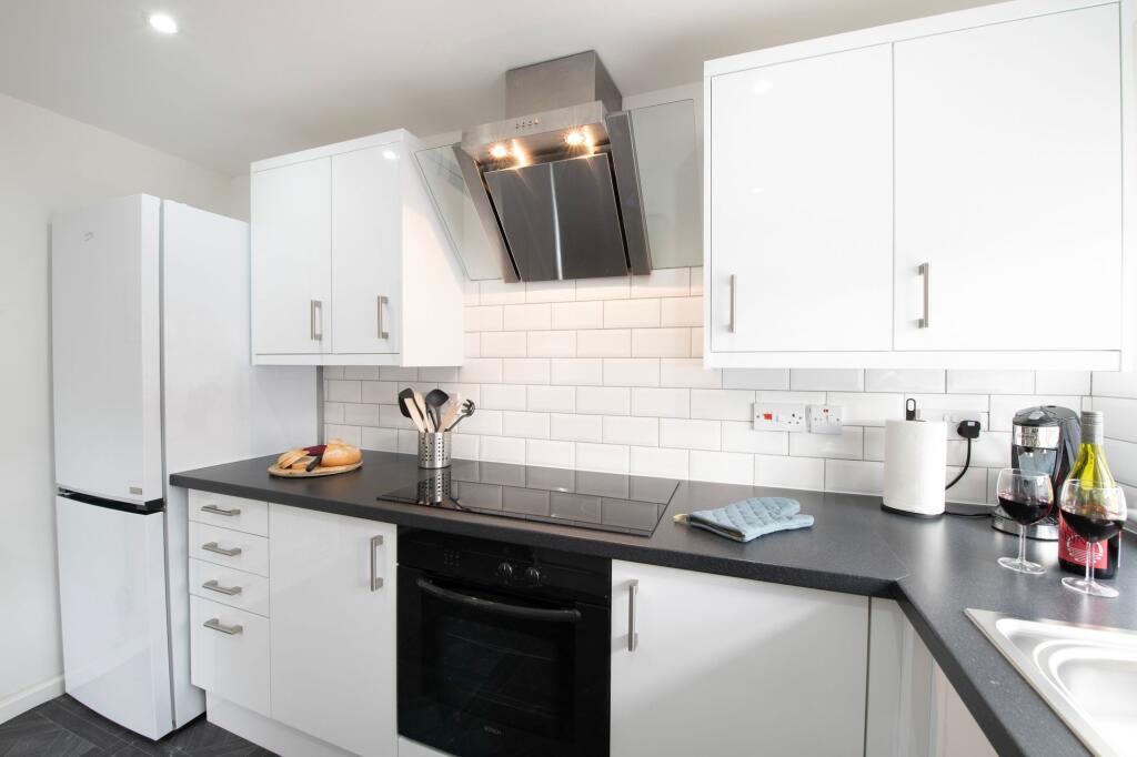 Modern and clean kitchen with white cabinets, a...