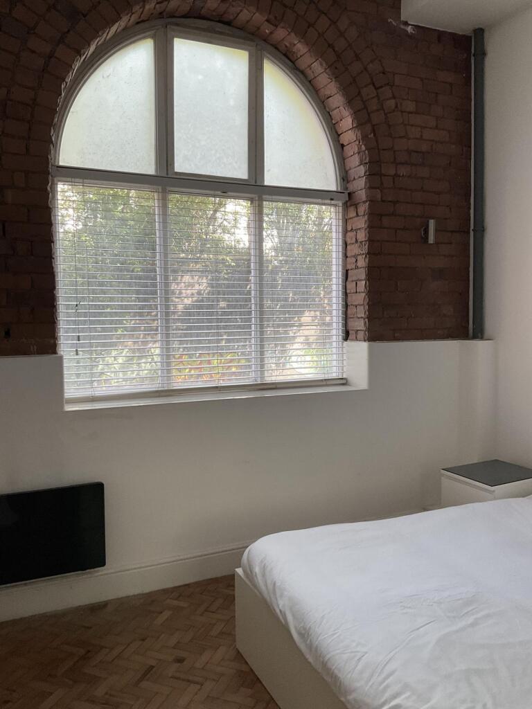 A cozy double bedroom featuring a large arched ...